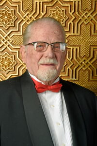 Older man in tuxedo and red bow tie